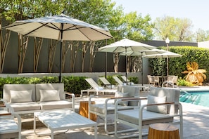 A poolside area with lounge chairs, umbrellas, and a pool. - DoubleTree by Hilton Hotel Austin Northwest Arboretum (Austin)
