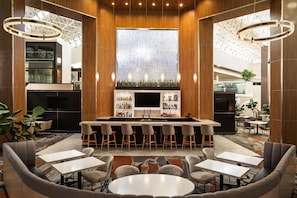 A modern bar area with a central island, bar stools, and seating arrangements. - DoubleTree by Hilton Hotel Austin Northwest Arboretum (Austin)