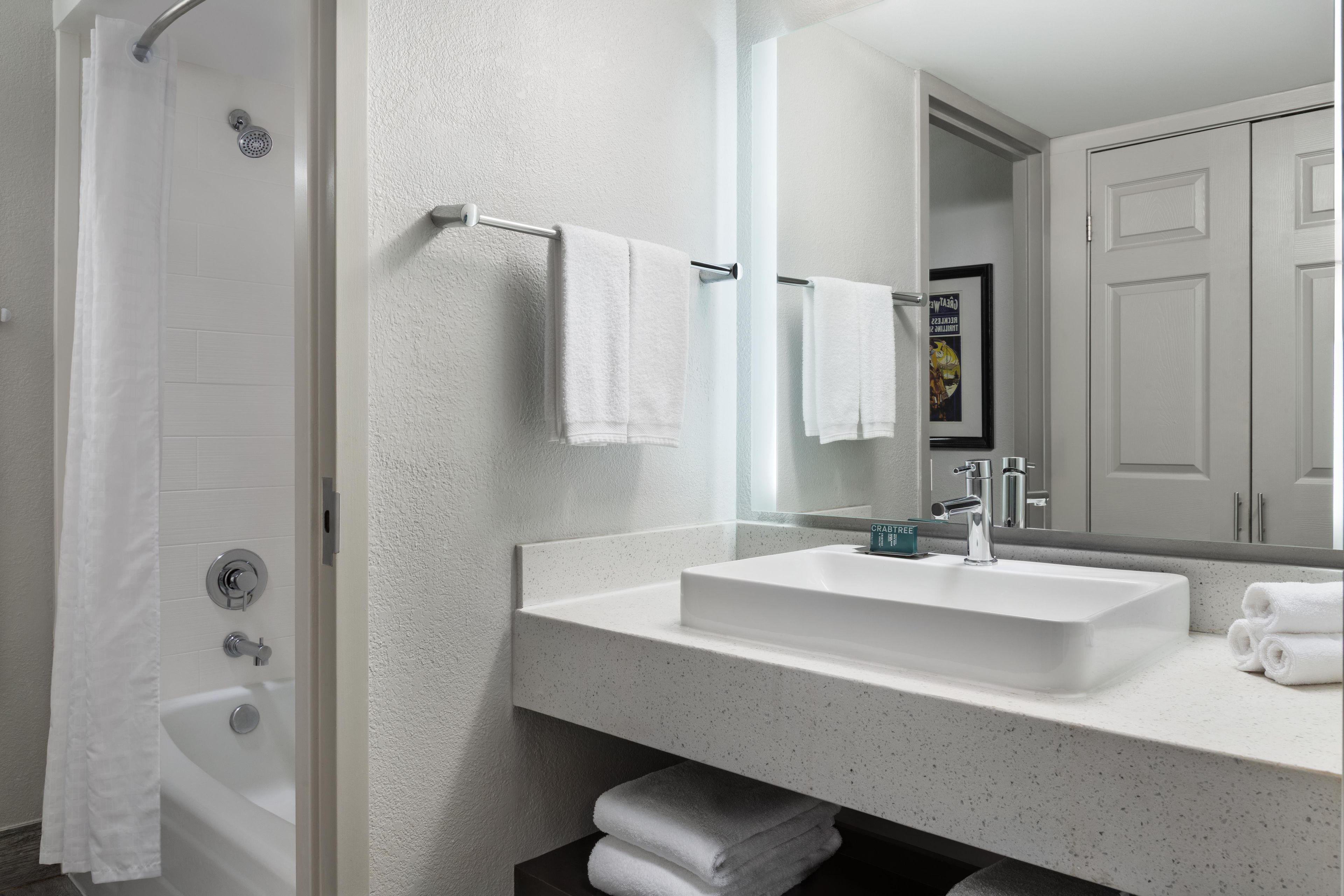 A modern bathroom with a white bathtub, a large mirror, and a sink with a chrome faucet.
