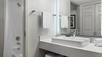 A modern bathroom with a white bathtub, a large mirror, and a sink with a chrome faucet.