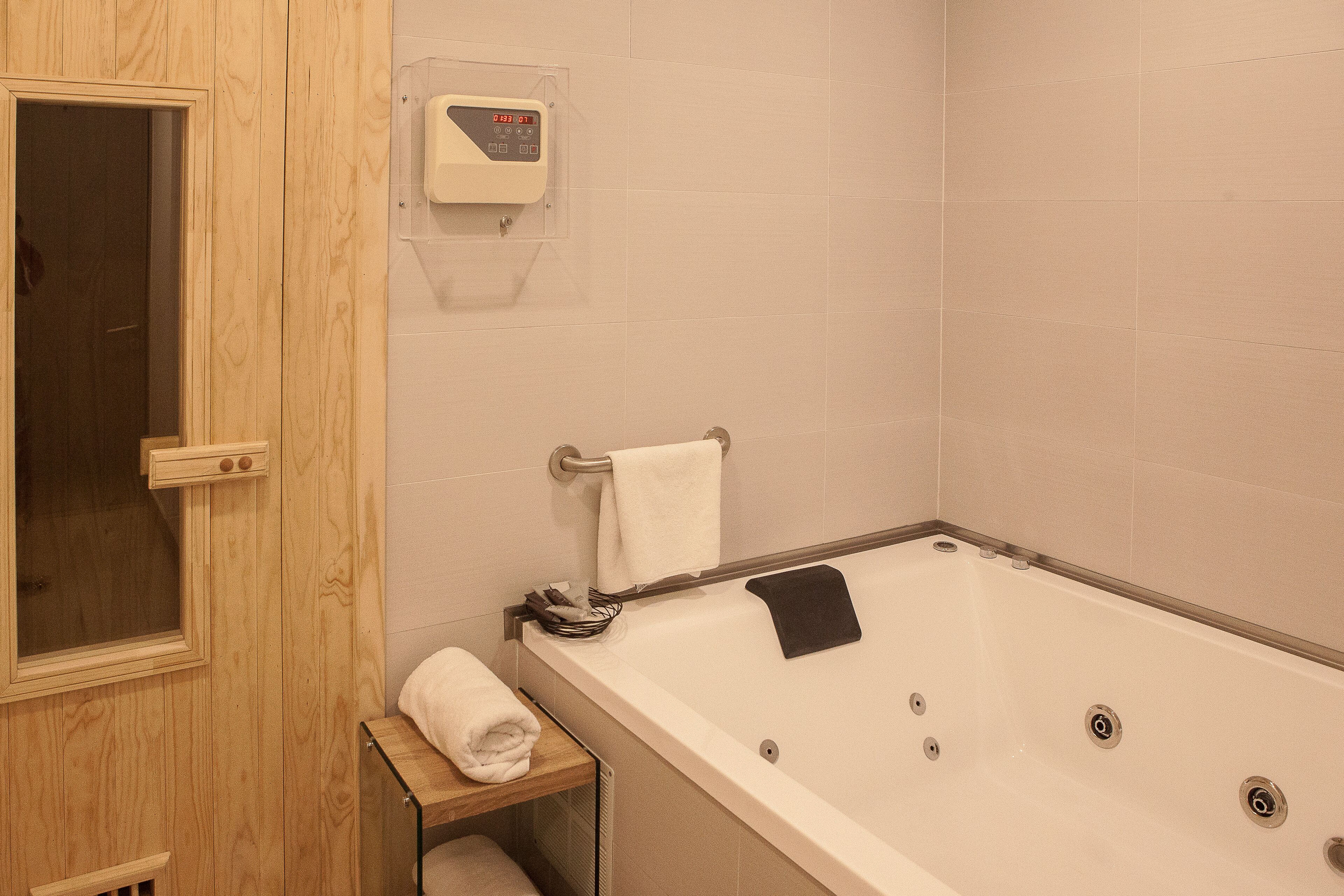Ein Badezimmer mit einer Holztür, einer Badewanne mit einem schwarzen Handtuch und einem Handtuchhalter.