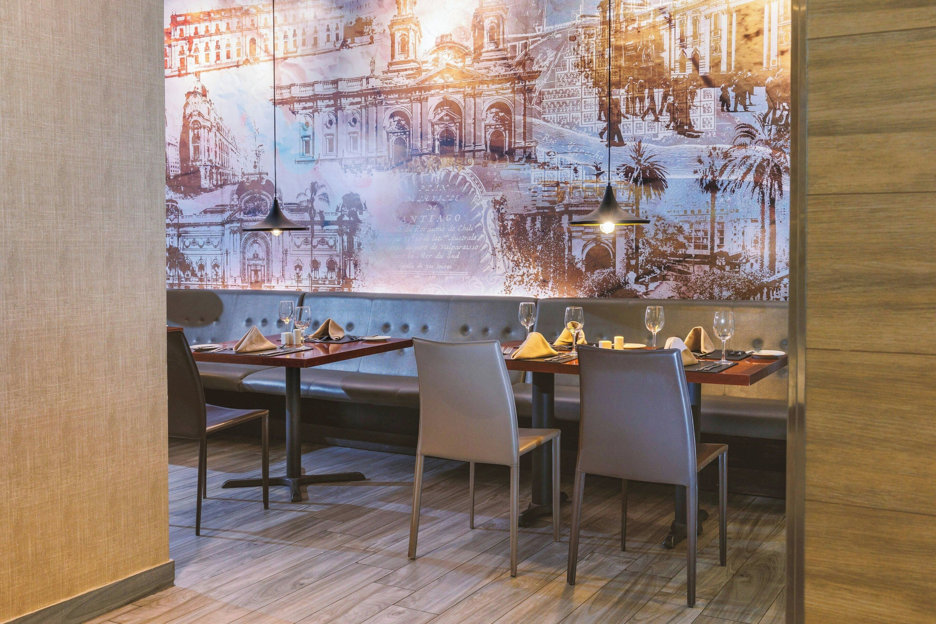 Un restaurante con un mural de un edificio histórico, mesas de madera y sillas modernas.
