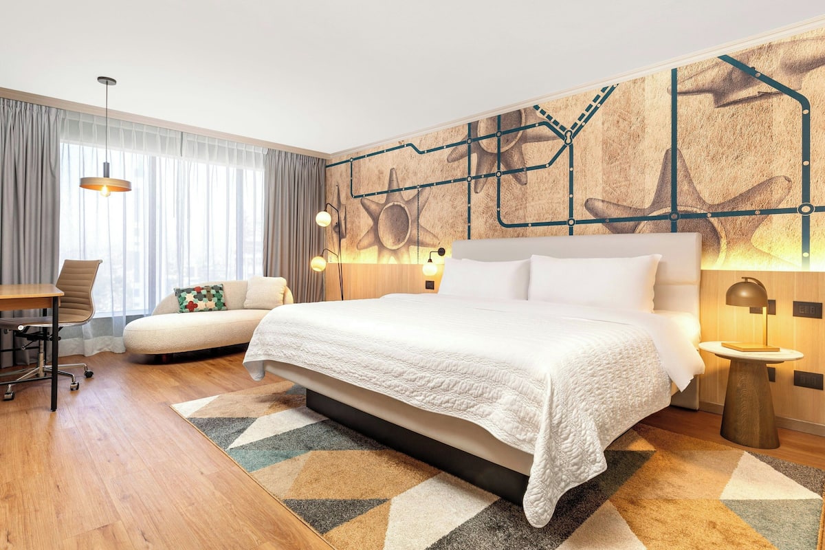 Una habitación de hotel moderna con una cama grande, un escritorio y un sofá.