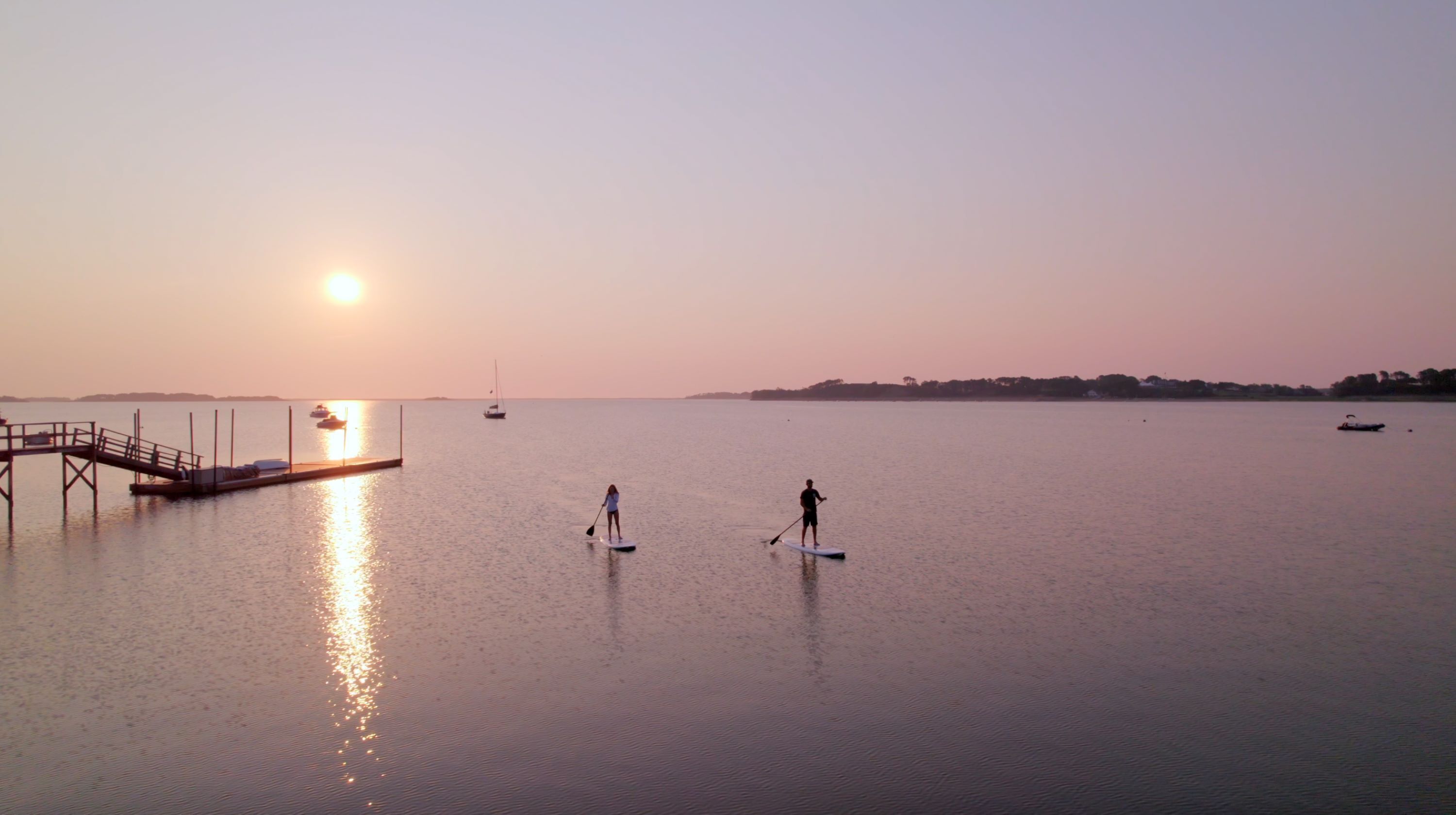 A calm body of water with a pier and boats.