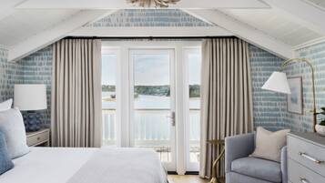 A bedroom with a large bed, a seating area, and a view of the outdoors.