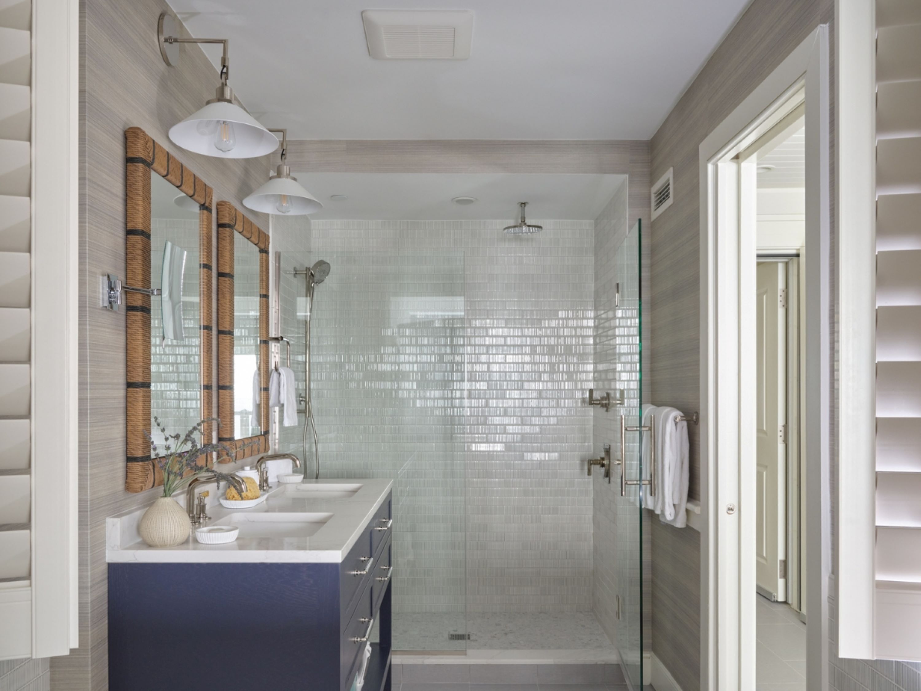 A modern bathroom with a glass-enclosed shower, a vanity with a mirror and two sinks, and a large mirror with a wooden frame.