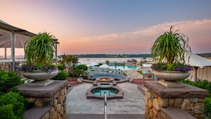 A pool area with lounge chairs and a fire pit, surrounded by stone walls and potted plants. - Wequassett Resort and Golf Club (Harwich)