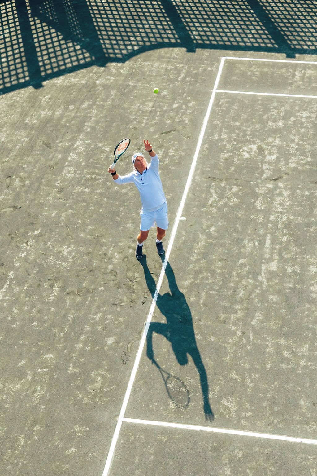 A tennis player on a court with a net and lines marking the boundaries.