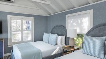 A bedroom with two beds, a TV, and a window with blinds.