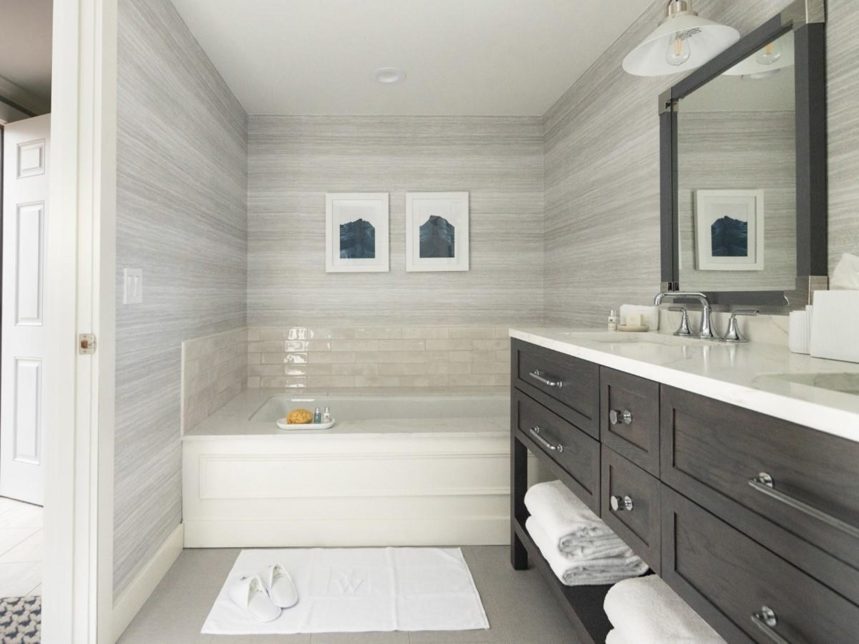 A modern bathroom with a bathtub, vanity, and a large mirror.