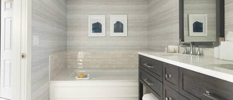 A modern bathroom with a bathtub, vanity, and a large mirror.