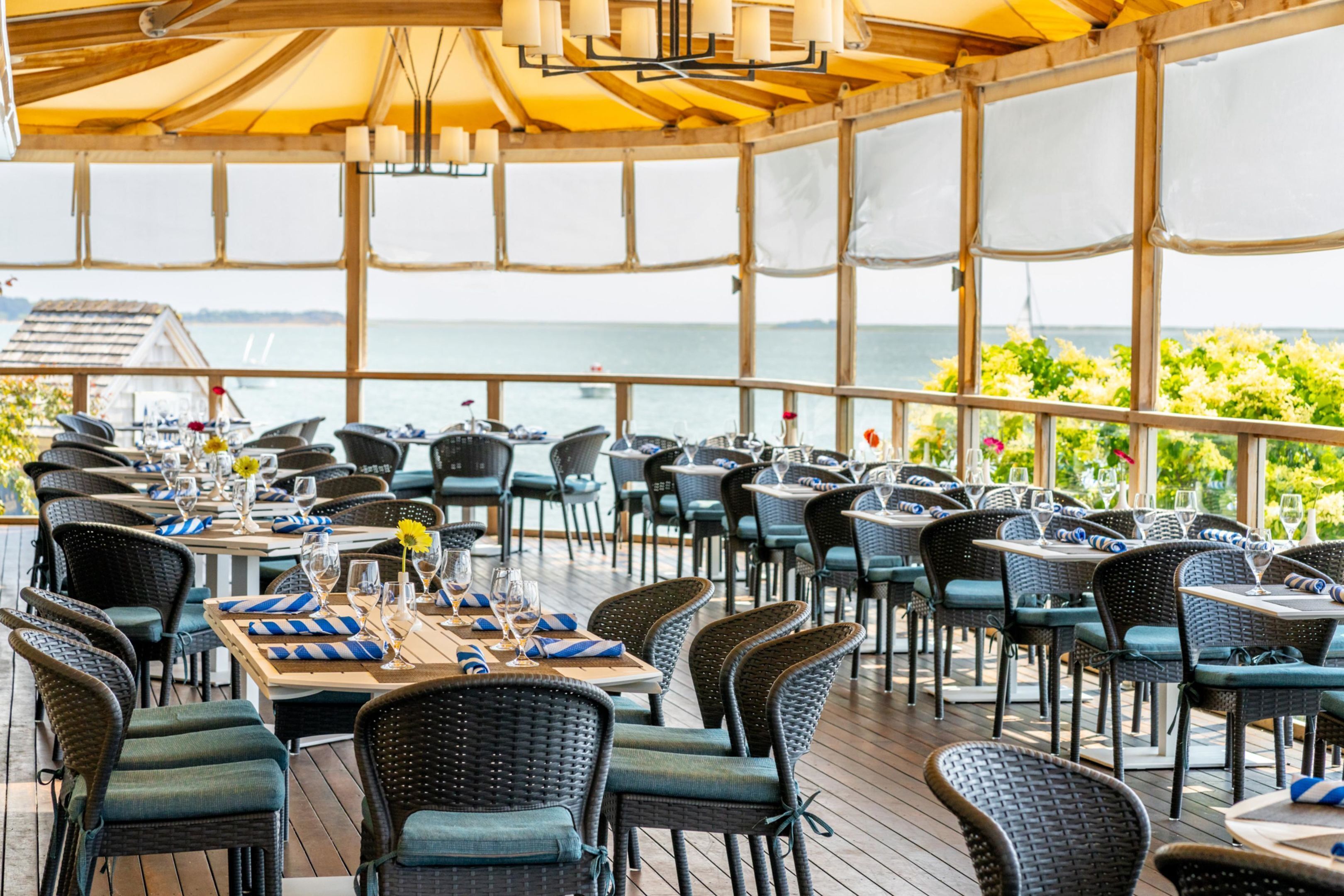 An outdoor dining area with tables and chairs, overlooking a body of water.