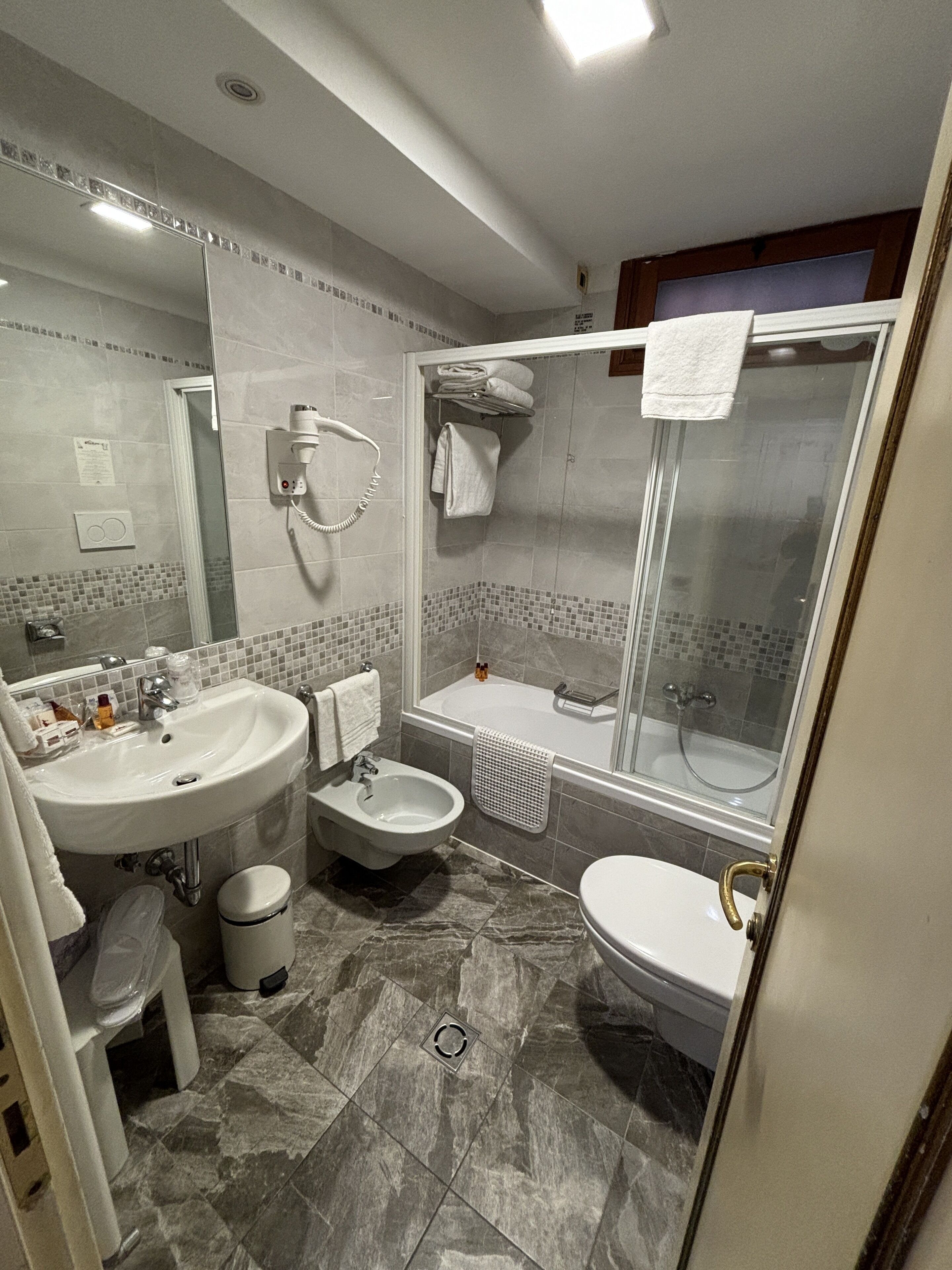 A modern bathroom with a sink, bidet, bathtub, and shower.