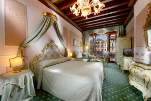 A luxurious bedroom with a large bed, a chandelier, and a view of the city through an open door.