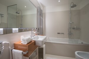 A modern bathroom with a glass-enclosed shower, a white sink, and a mirror above the vanity.