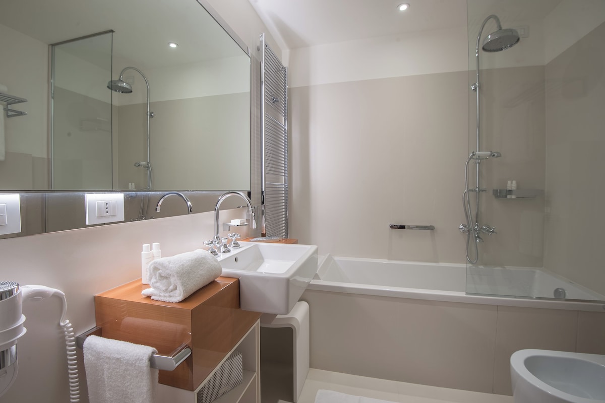 Un baño moderno con ducha de vidrio, un lavamanos blanco y un espejo sobre el mueble.
