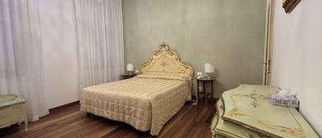 A hotel room with a large bed, a chandelier, a dresser, and a mirror.