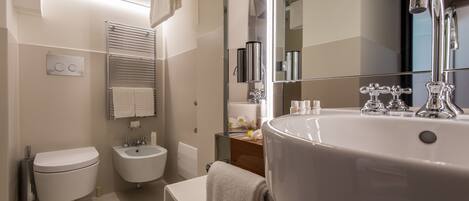 A modern bathroom with a toilet, bidet, and a large sink with a mirror.