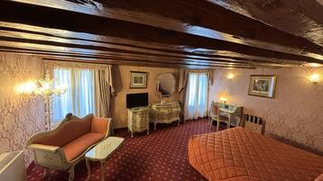 Una habitación con alfombra roja, sofá, cama, escritorio, espejo y candelabro.