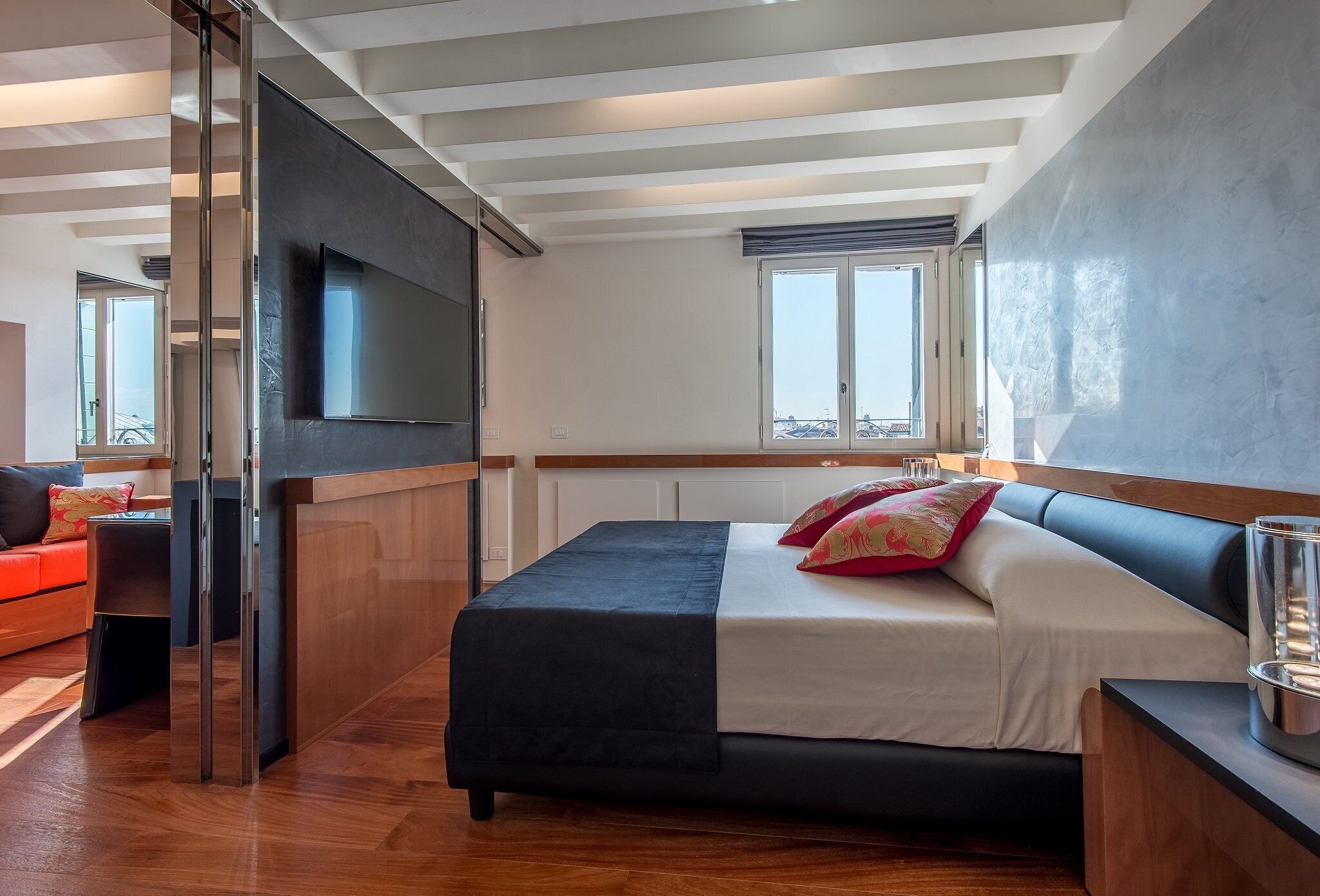 A modern bedroom with a bed, a TV, and a window.