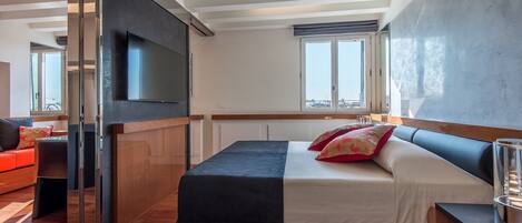 A modern bedroom with a bed, a TV, and a window.
