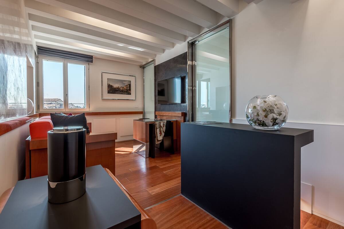A modern living room with a wooden floor, a sofa, a coffee table, and a TV mounted on the wall.