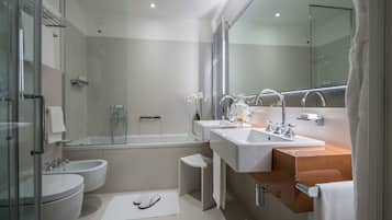 Een moderne badkamer met een douchecabine van glas, twee wasbakken, een toilet met bidetfunctie en een grote spiegel.