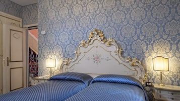 Quarto com uma cama grande e ornamentada, duas mesas de cabeceira com abajures e um papel de parede estampado.