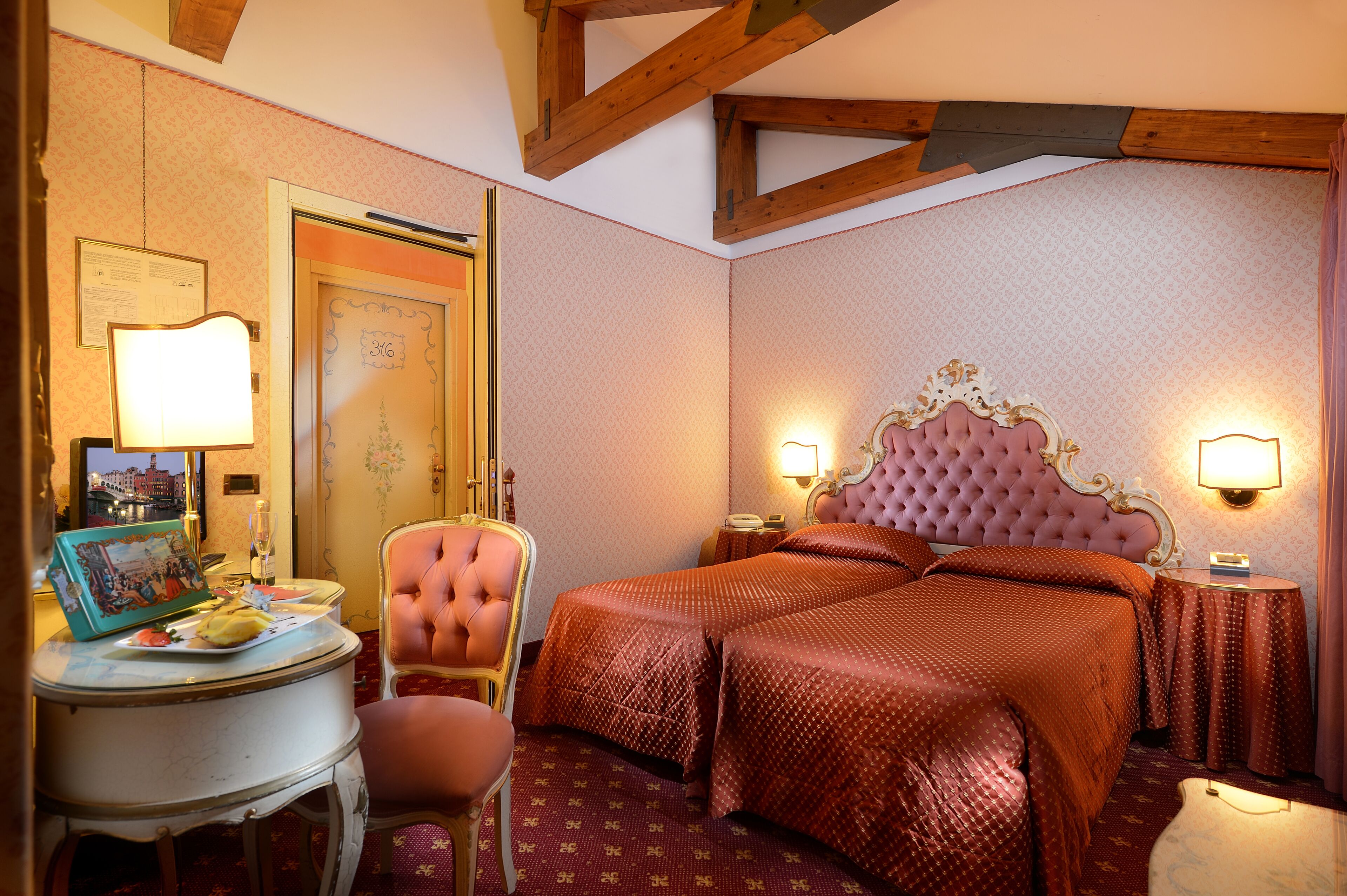 A hotel room with a large bed, a chair, a small table, and a lamp.
