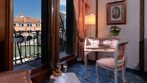 A room with a balcony, a desk, a chair, a lamp, and a framed picture. - Hotel Rialto (Venice)
