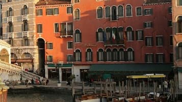 A historic building with a prominent tower, a canal with boats, and a bridge in the foreground.