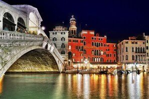 A historic bridge over a canal with a red building labeled "HOTEL RIALTO" in the background.