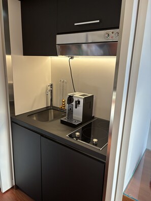 A compact kitchen with a built-in espresso machine, a sink, and a stovetop.