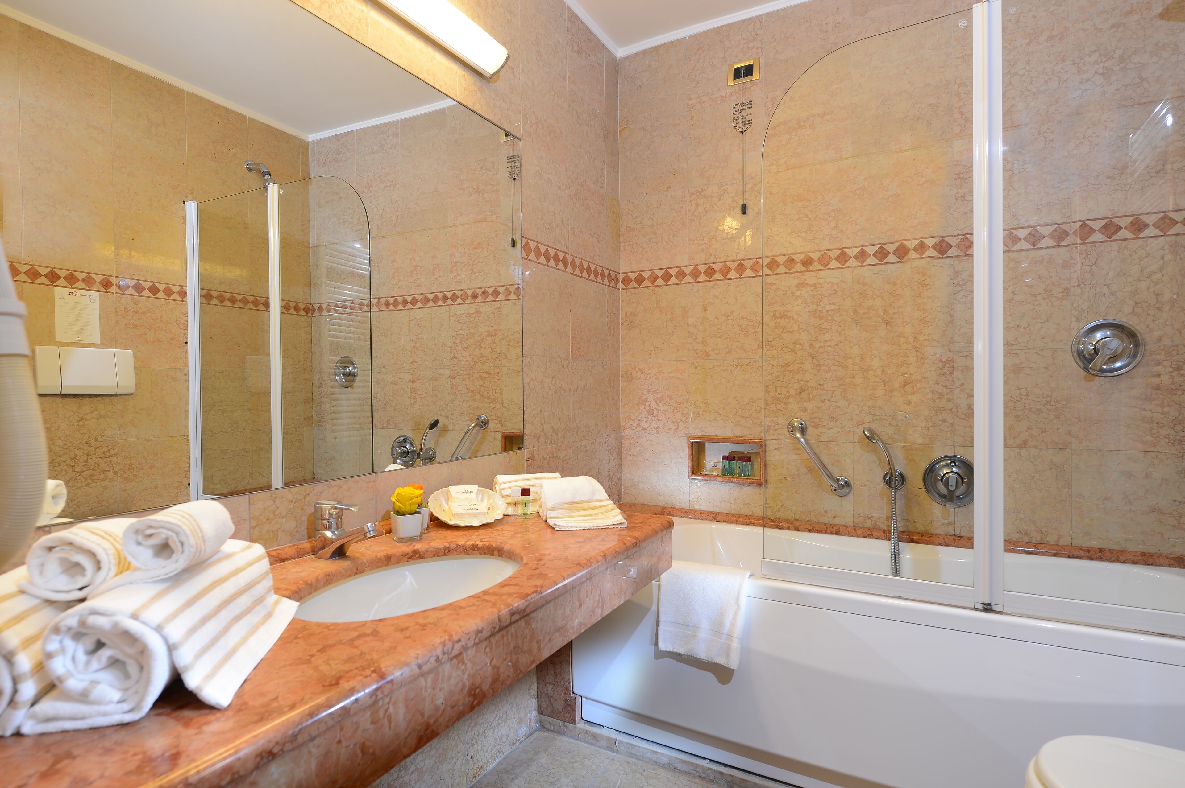 A bathroom with a marble sink, a glass-enclosed shower, and a white bathtub.