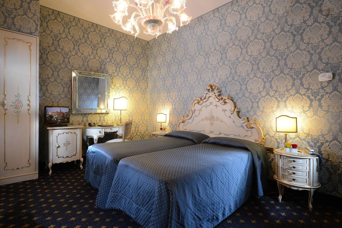 A bedroom with two beds, a dresser, a vanity, and a chandelier.