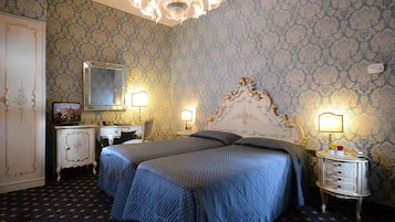 Une chambre avec deux lits, une commode, une coiffeuse et un lustre.
