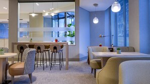 Een moderne eethoek met een centraal eiland, barstoelen en diverse zitplaatsen, waaronder een zitbankje en losse stoelen.