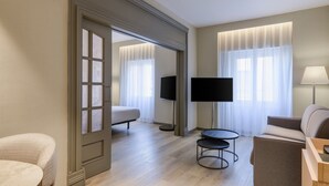 Een moderne hotelkamer met een bed, een bank, een televisie, een lamp en een kleine tafel.