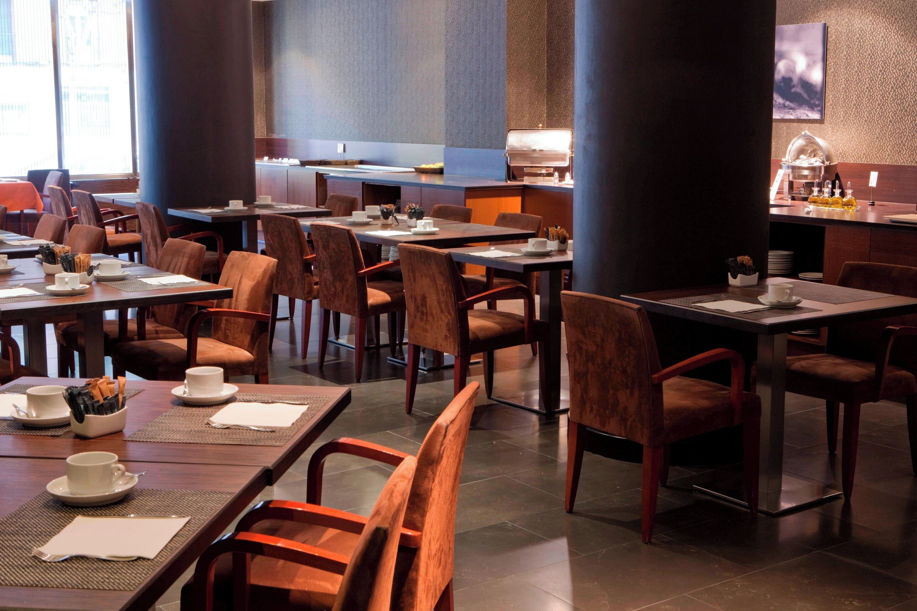 Un restaurant doté de nombreuses tables et chaises, d’un espace buffet et d’un coin café.