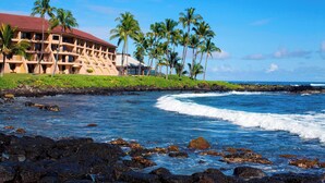 A beachfront hotel with multiple balconies, palm trees, and a view of the ocean. - Sheraton Kauai Resort (Koloa)