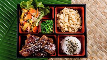 En bento-låda med olika sorters mat, inklusive ris, kött, grönsaker och makaroner.