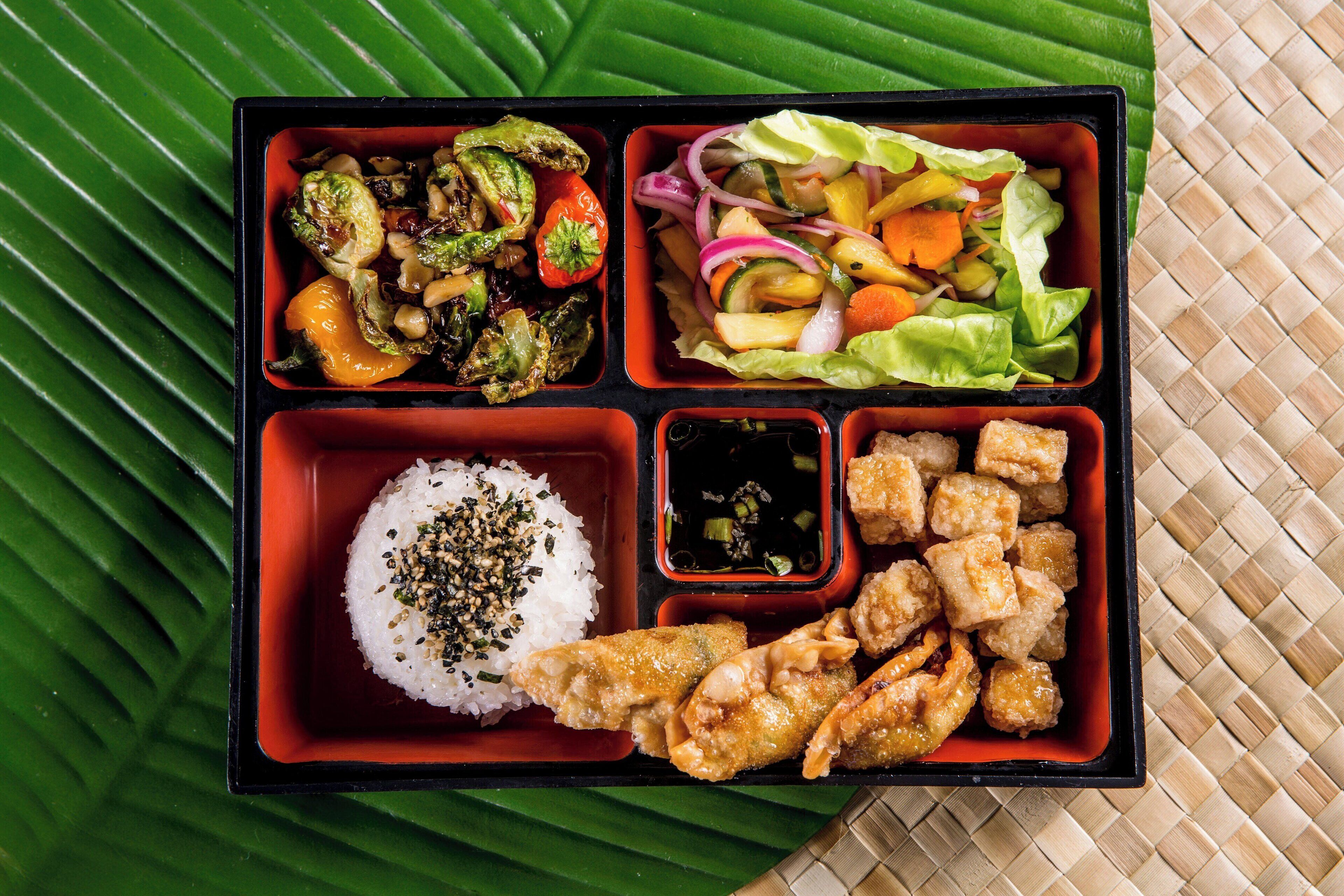 Una caja bento con arroz, verduras y alimentos fritos.