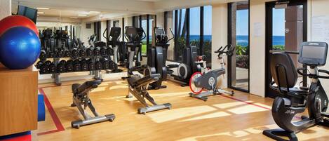 A gym with cardio machines, free weights, and exercise balls.