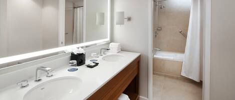Un baño moderno con dos lavamanos, un espejo grande y una zona de ducha.