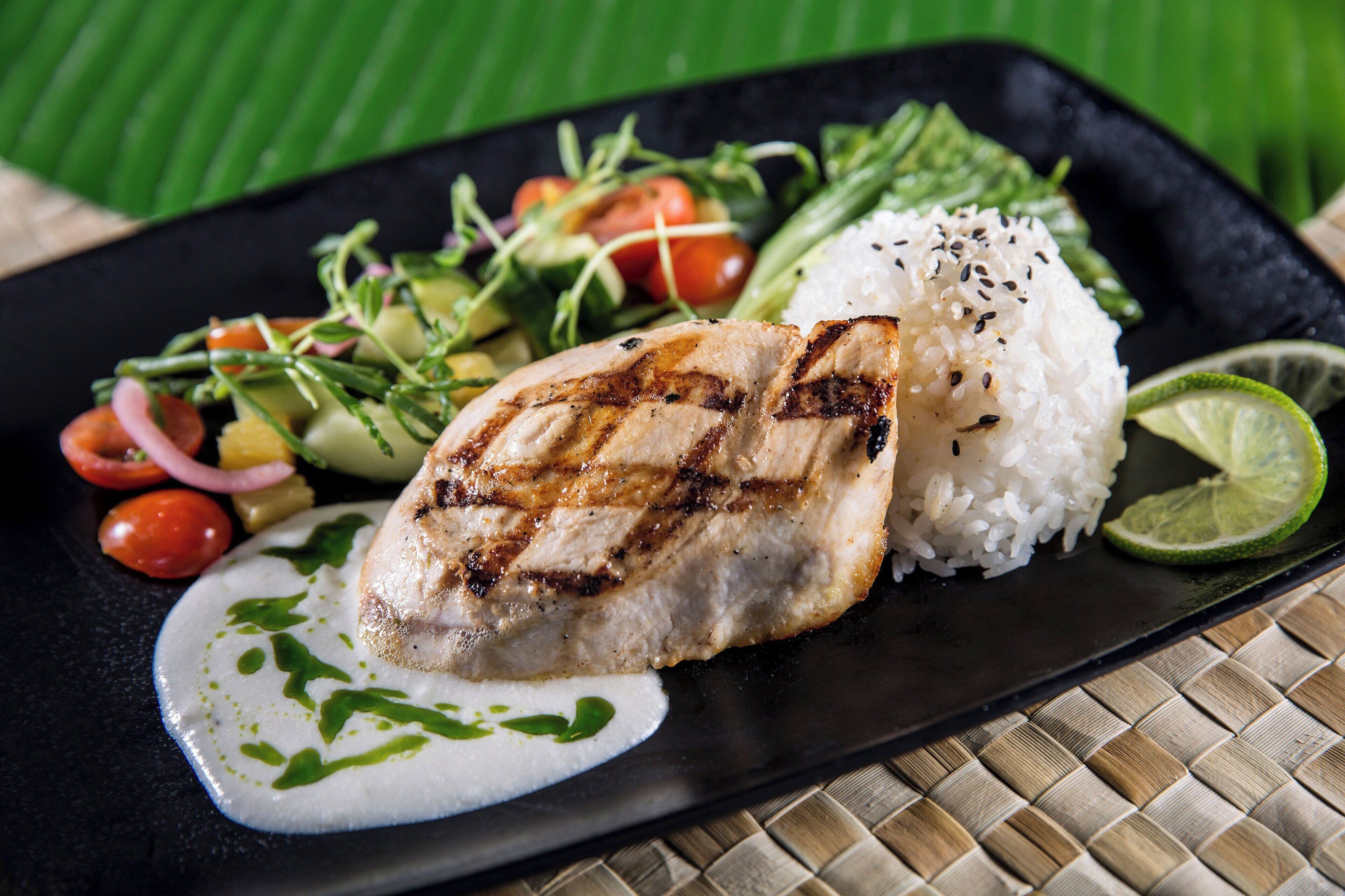 A plate with grilled chicken, rice, and a side salad.