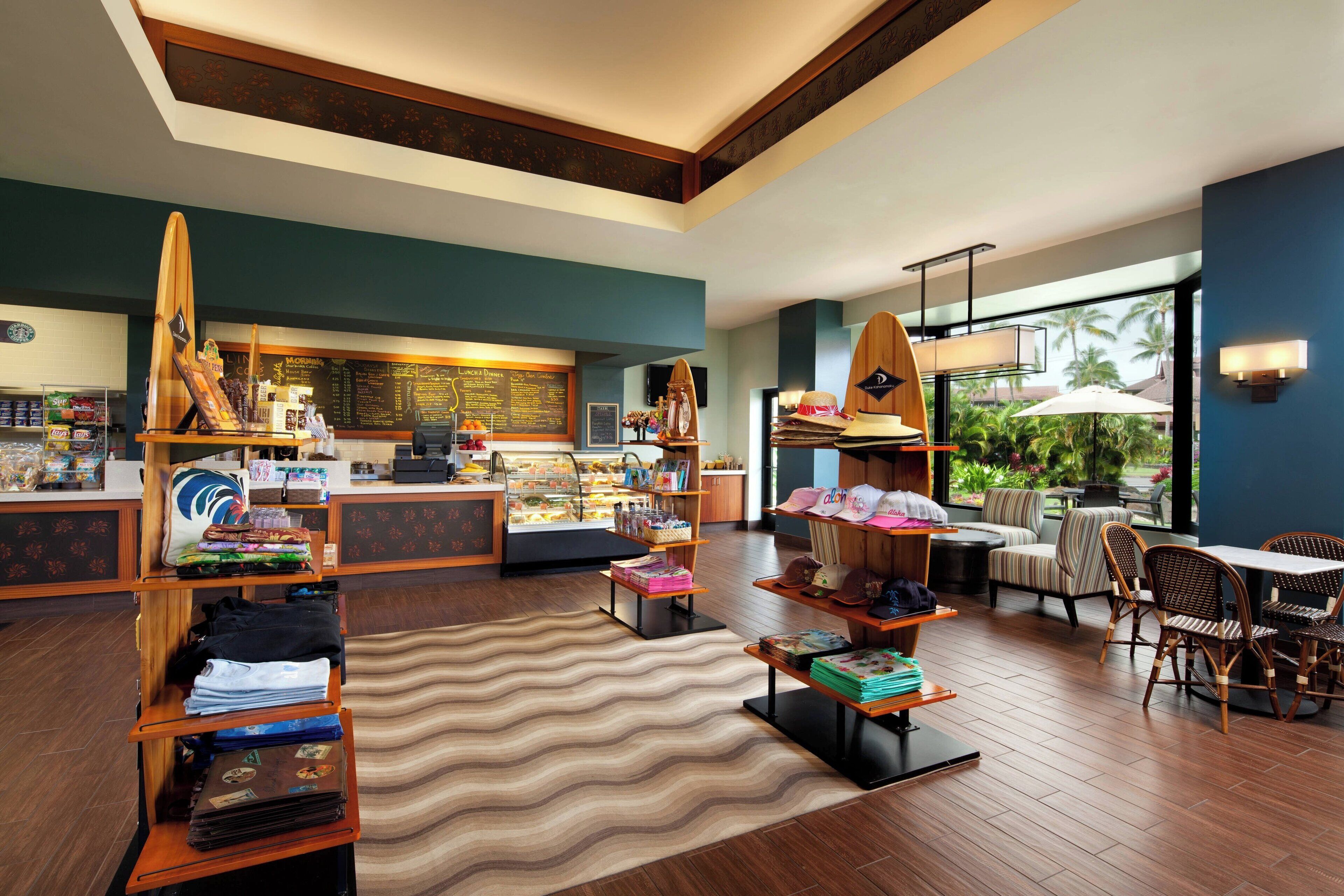 A modern hotel lobby with wooden furniture, a central seating area, and a view of the outdoors through large windows.