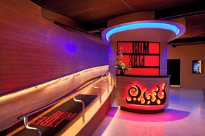 A reception area with a curved desk, a wooden bench, and a staircase with a 'RUNWAY' sign.