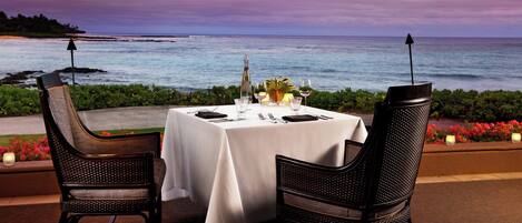 Una mesa para dos con vista al océano al atardecer.