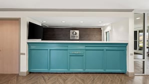 Una cocina moderna con armarios azul verdoso, encimera blanca y un letrero que dice 'Quality'.