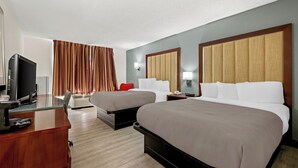 Habitación de hotel con dos camas, televisor, escritorio y ventana con cortinas.